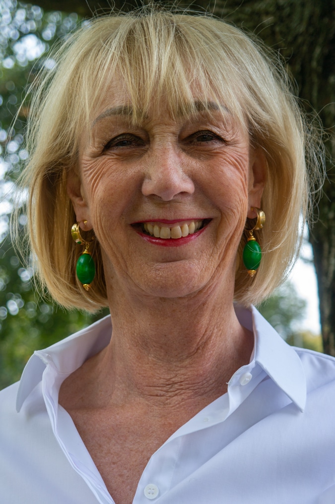 Green and golden earrings by Lara Design with a white shirt