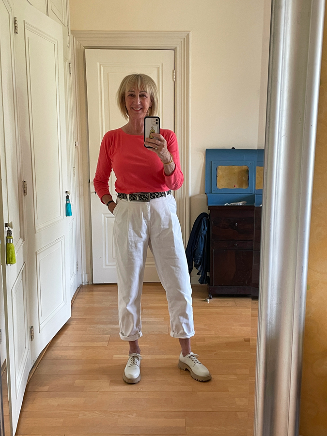 Coral coloured top and white trousers