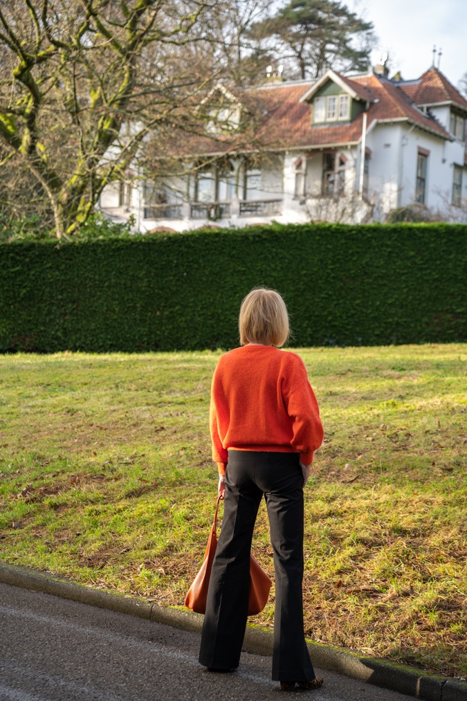 Flared black trousers with an orange jumper