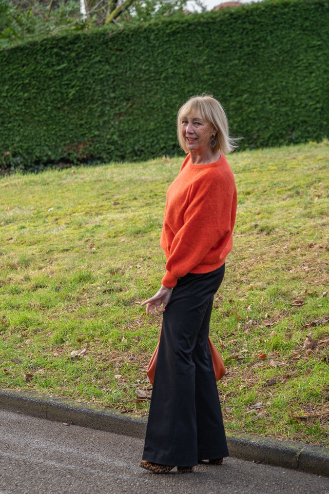 Flared black trousers with an orange jumper