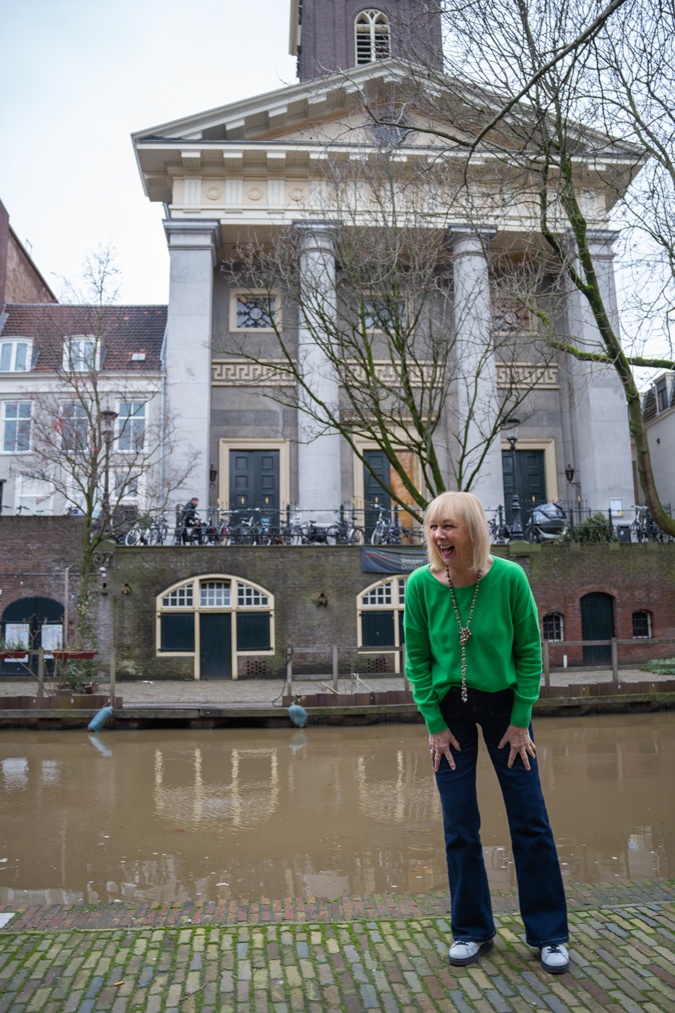 green jumper with flared jeans and trainers
