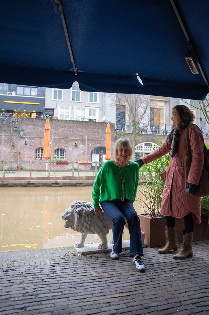 green jumper with flared jeans and trainers