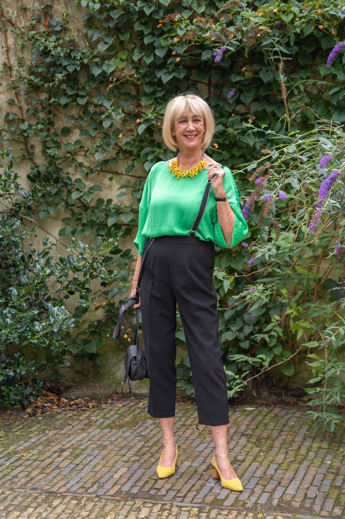 Black summer trousers with a green top and yellow necklace