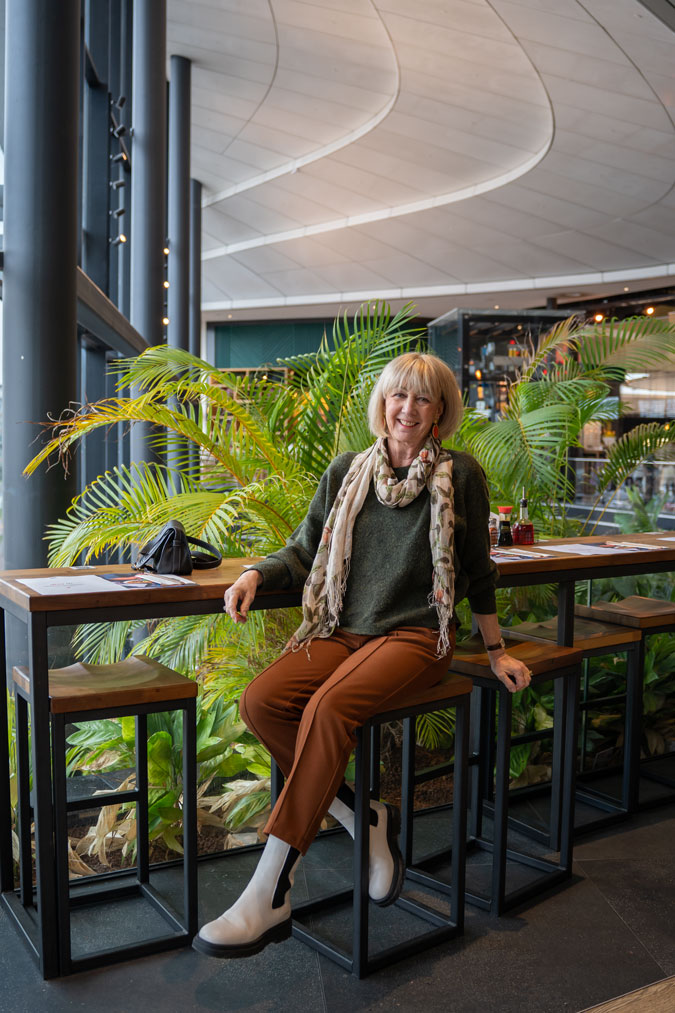 Cognac coloured trousers with a green jumper and a scarf