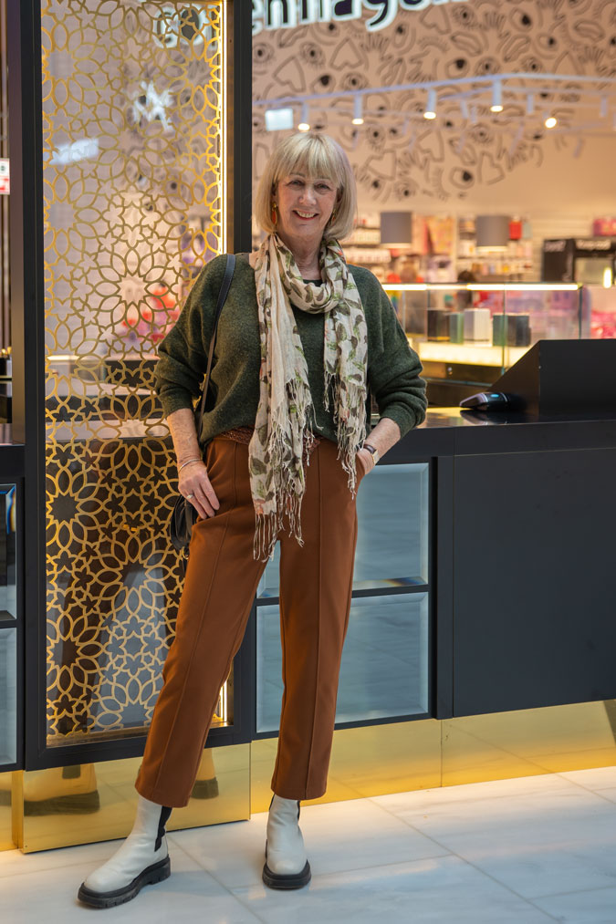 Cognac coloured trousers with a green jumper and a scarf
