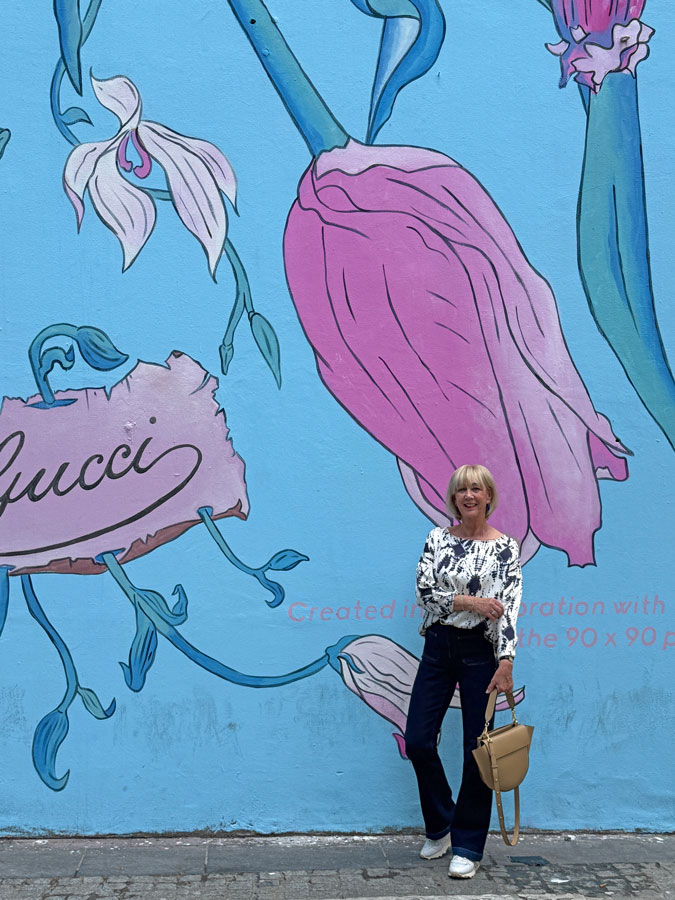 Blue and white top with jeans against the Gucci wall