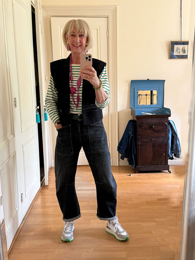 Barrel jeans with a green and white striped shirt, a black waistcoat and a pink necklace