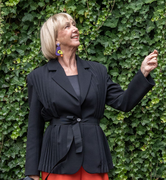 Pleated black blazer with statement earrings.
